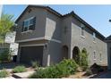 Exterior home elevation showing neutral stucco, tiled roof, desert landscaping, and a two-car attached garage at 6631 Frosted Harvest Ave, Las Vegas, NV 89108