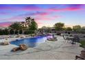 An inground pool with rock waterfall feature and patio seating under a dramatic twilight sky at 6907 Kelp Ledge Ct, Las Vegas, NV 89131