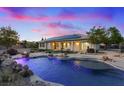 Backyard with a pool featuring custom rock accents and a covered patio under a pink and blue sky at 6907 Kelp Ledge Ct, Las Vegas, NV 89131