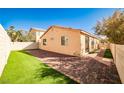 A cozy backyard featuring artificial grass, brick pavers, and a well-maintained block wall fence at 5575 Cresent Valley St, Las Vegas, NV 89148