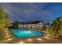 Inviting backyard oasis with a sparkling pool, manicured landscaping, and ambient lighting for evening enjoyment at 5858 Majestic Tide Ave, Las Vegas, NV 89131