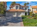 Stunning two-story home featuring a tile roof, three-car garage, and lush landscaping under a clear blue sky at 8848 Rainbow Ridge Dr, Las Vegas, NV 89117