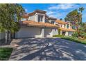 Inviting two-story home featuring a three-car garage and desert landscaping, with mature trees providing shade at 8848 Rainbow Ridge Dr, Las Vegas, NV 89117