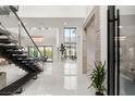 Bright, open foyer with soaring ceilings, statement staircase, and eye-catching chandelier and modern tile flooring at 10752 Patina Hills Ct, Las Vegas, NV 89135
