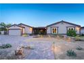 Charming single-story home boasts desert landscaping, a spacious driveway, and a welcoming facade with warm lighting at 197 Ebb Tide Cir, Las Vegas, NV 89123