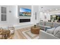 Elegant living room showcasing a fireplace, beach scenery on TV, cozy seating, and natural light from shuttered windows at 5225 Villa Dante Ave, Las Vegas, NV 89141