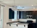 Modern kitchen featuring dark cabinetry, granite countertops, stainless steel appliances, and a decorative chandelier at 5653 Nobleton Ct, North Las Vegas, NV 89081