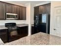 Stylish kitchen with black appliances, dark cabinets, granite countertops, and a built-in wine rack at 5653 Nobleton Ct, North Las Vegas, NV 89081