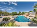 A stunning pool area with a rock waterfall, spa, and mature landscaping for a relaxing outdoor experience at 7760 Haven St, Las Vegas, NV 89123