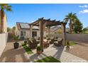 Backyard features a pergola-covered fire pit sitting area surrounded by lush landscaping at 7957 Lovely Pine Pl, Las Vegas, NV 89143