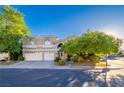 Traditional style home with three car garage, desert landscaping, and lush mature trees at 1925 Grey Eagle St, Henderson, NV 89074