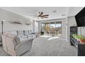 Bright living room featuring neutral carpet, ceiling fan, and sliding glass doors at 2383 Elmont Ave, North Las Vegas, NV 89086