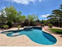 Inviting pool area with a spa, lush landscaping, and a clear blue sky at 2554 Braehead Ln, Henderson, NV 89044