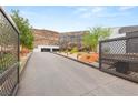 Gated driveway leading to a modern home with a striking rock facade and mountain backdrop at 3 Horseshoe Rock Ct, Henderson, NV 89012