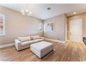 Comfortable living room featuring wood flooring, white couch, ottoman, and white trimmed windows at 601 Bear Grass St, Las Vegas, NV 89144