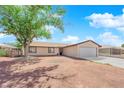 Single-story home with neutral paint, a well-manicured front yard and large shade tree at 608 W Mcdermit St, Las Vegas, NV 89107