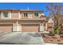 Townhome featuring three garage doors, tile roof, well maintained landscaping and neutral color scheme at 632 Twilight Blue Ave, North Las Vegas, NV 89032