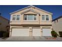 Beige two-story townhome featuring a multi-car garage and well-maintained landscaping at 9343 Leaping Deer Pl # 103, Las Vegas, NV 89178