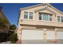 Beige two-story townhome featuring a multi-car garage and well-maintained landscaping at 9343 Leaping Deer Pl # 103, Las Vegas, NV 89178