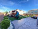 Fully landscaped backyard features a playground, swing set, synthetic grass and pavers at 10152 Tenaya Meadows St, Las Vegas, NV 89178