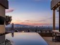 Infinity pool overlooking city lights with outdoor seating areas and a covered outdoor bar at 1491 Reims Dr, Henderson, NV 89012