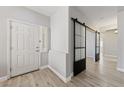 Bright foyer with modern sliding barn door accent and beautiful light wood-look flooring throughout at 51 La Fiesta St, Henderson, NV 89012