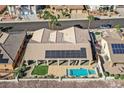 A high aerial shot displays a pool with solar and a covered patio, and lush landscaping to enjoy at 904 Rhyolite Ter, Henderson, NV 89011