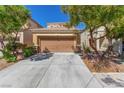 Charming beige home with a two-car garage, desert landscaping, and a concrete driveway at 9773 Bedstraw St, Las Vegas, NV 89178