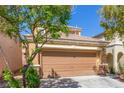 Beige two-story home with a large two-car garage, complemented by mature trees at 9773 Bedstraw St, Las Vegas, NV 89178