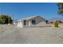 Quaint one-story home with a gravel driveway, mountain views, and a covered porch at 1450 Fern St, Pahrump, NV 89060