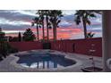 Backyard swimming pool and palm trees silhouetted against a vibrant and colorful sunset sky at 1766 Baja Ln, Henderson, NV 89012