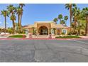 View of the well-maintained clubhouse exterior entrance with manicured lawns and desert landscaping with tall palm trees at 2120 Ramrod Ave # 513, Henderson, NV 89014