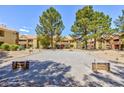 A horseshoe pit is nestled between condo buildings, shaded by mature trees, offering residents a recreational space at 2120 Ramrod Ave # 513, Henderson, NV 89014