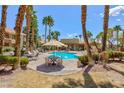 Outdoor pool with a lounge area and tables, surrounded by palm trees and well-maintained landscaping at 2120 Ramrod Ave # 513, Henderson, NV 89014