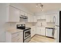 Bright kitchen featuring modern appliances, white cabinets, light countertops, and contemporary fixtures at 3151 Soaring Gulls Dr # 2002, Las Vegas, NV 89128