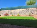A well kept backyard showing artifical turf surrounded by rock and plants at 3567 Cottage Stream Ct, Laughlin, NV 89029