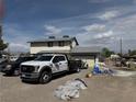 Angle shot of the two-story home, showing the dirt front yard and vehicles in the driveway at 664 Spring Rd, Indian Springs, NV 89018