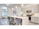 Bright kitchen with stainless steel appliances, a quartz countertop island, and pendant lighting overlooking living area at 1157 Blossom Point St, Las Vegas, NV 89135