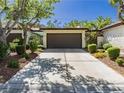 Single story home featuring a two car garage and mature landscaping along the driveway at 4567 Madreperla St, Las Vegas, NV 89121