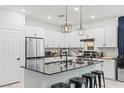 Modern kitchen features white cabinets, stainless steel appliances, and a black countertop island at 6848 Calvitero St, Las Vegas, NV 89149