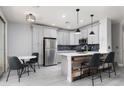 Eat-in kitchen features stainless appliances, breakfast bar with chairs, and modern pendant lighting at 689 Principle Point Ave, Henderson, NV 89012