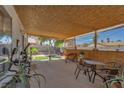 Inviting covered patio with a bamboo ceiling, outdoor seating, and views of the landscaped backyard at 7055 Sylvan Oak Dr, Las Vegas, NV 89147