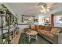 Cozy living room featuring a plush sofa, decorative plants, and a large mirror enhancing the bright and airy ambiance at 7055 Sylvan Oak Dr, Las Vegas, NV 89147