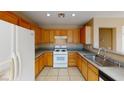 Functional kitchen with wooden cabinets, tile flooring, and modern white appliances at 10245 Missouri Meadows St, Las Vegas, NV 89183