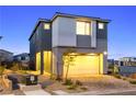 Dusk view of a modern two-story home with gray and white exterior, two-car garage, and desert landscaping at 11800 Black Canary Ave, Las Vegas, NV 89138