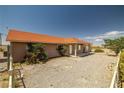 View of the side of a well-maintained single-story home, complemented by mature landscaping, and a gravel yard at 2090 S Ambush St, Pahrump, NV 89048