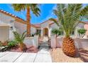 Inviting white home with gated courtyard, desert landscaping, and mature palm trees at 2377 Baldwinville Ct, Henderson, NV 89044
