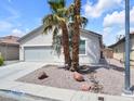 A well-kept single-story house with a two-car garage, desert landscaping, and sidewalks at 3032 Hartley Cove Ave, North Las Vegas, NV 89081