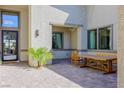 Relaxing outdoor patio area featuring brick pavers, a wooden dining table, and desert plants at 8310 W Camero Ave, Las Vegas, NV 89113
