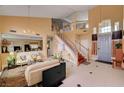 Bright, open living room with tall ceilings, tile floors, staircase, and view into the kitchen at 8983 Emerald Waters Ct, Las Vegas, NV 89147